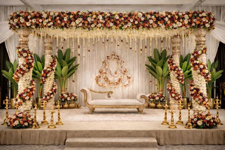 Elegant engagement stage decoration with floral pillars, white and gold sofa, and premium indoor wedding décor in Hyderabad.