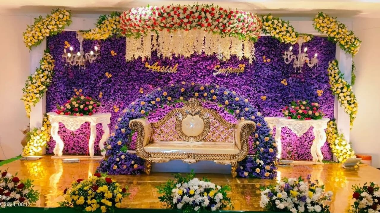 Elegant reception stage decoration with purple floral wall, chandelier lighting, and luxury seating setup in Hyderabad.
