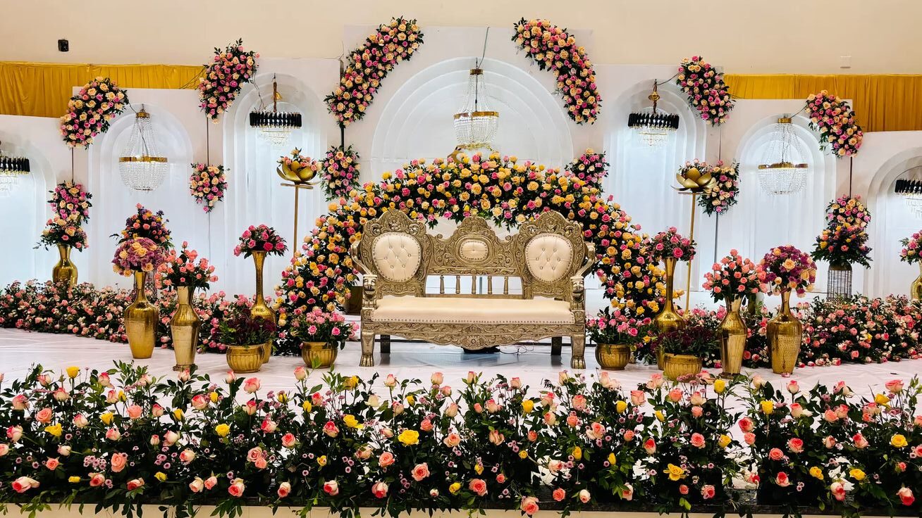 Elegant floral engagement stage decoration with pastel roses, chandelier lighting, and royal sofa setup in Hyderabad.
