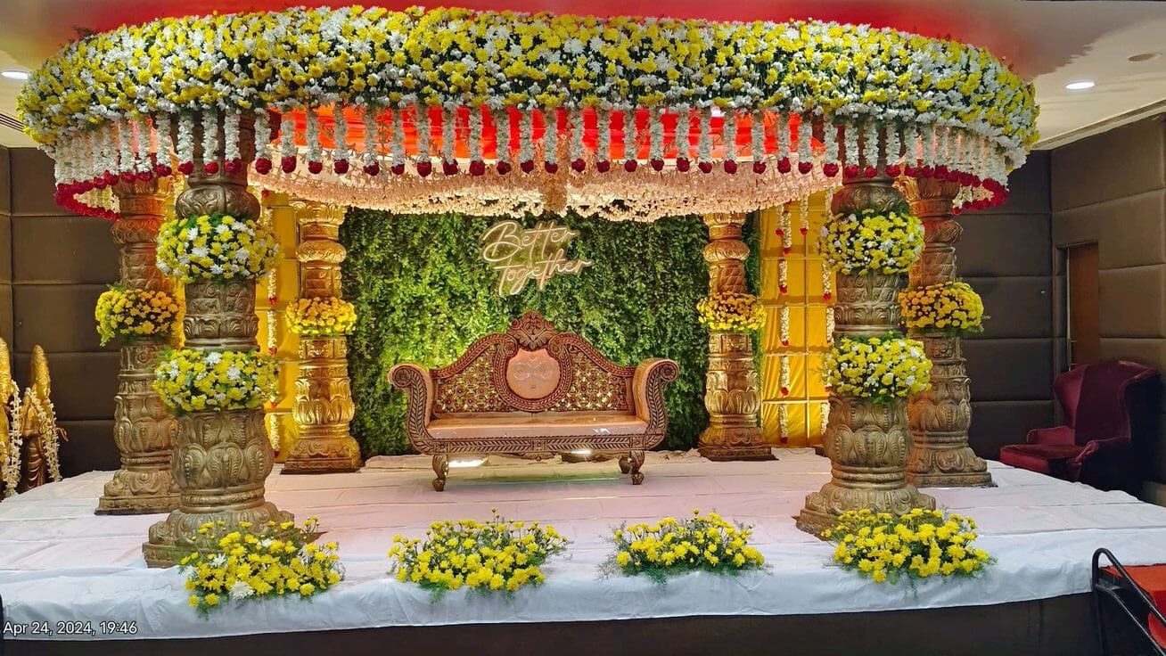 Elegant engagement stage decoration with yellow and white floral canopy and premium couple seating setup in Hyderabad.