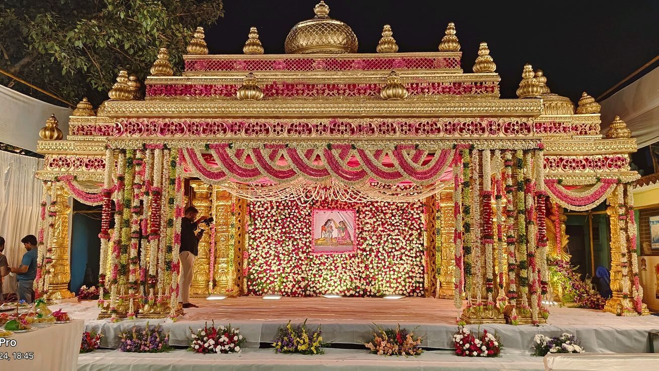 Beautiful grand traditional wedding mandap decoration with pink floral garlands and royal golden temple-style backdrop in Hyderabad.